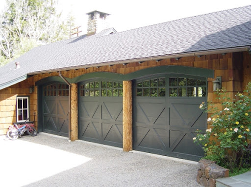 Triple black wood garage door on a light brown residential home